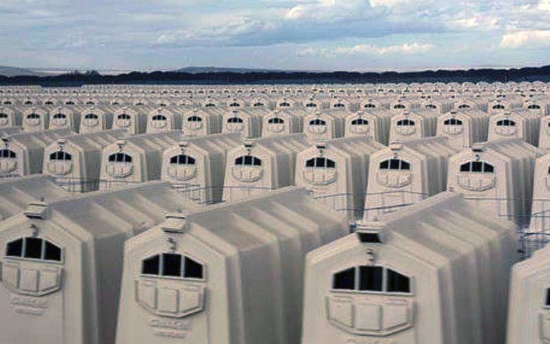 Close view of a large number of individual calf hutches aligned outdoors.