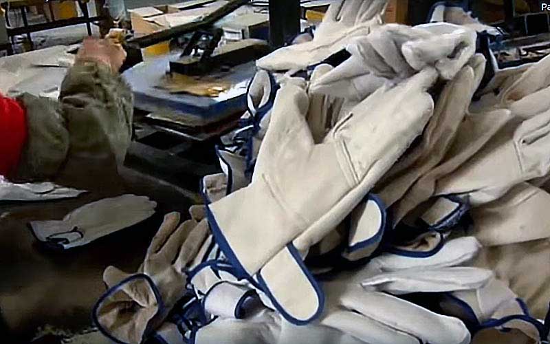 A pile of white leather work gloves displayed in a factory or workshop.