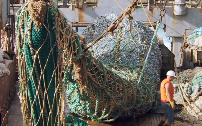 A wider view of a ship's deck showing large fishing nets and gear being handled.